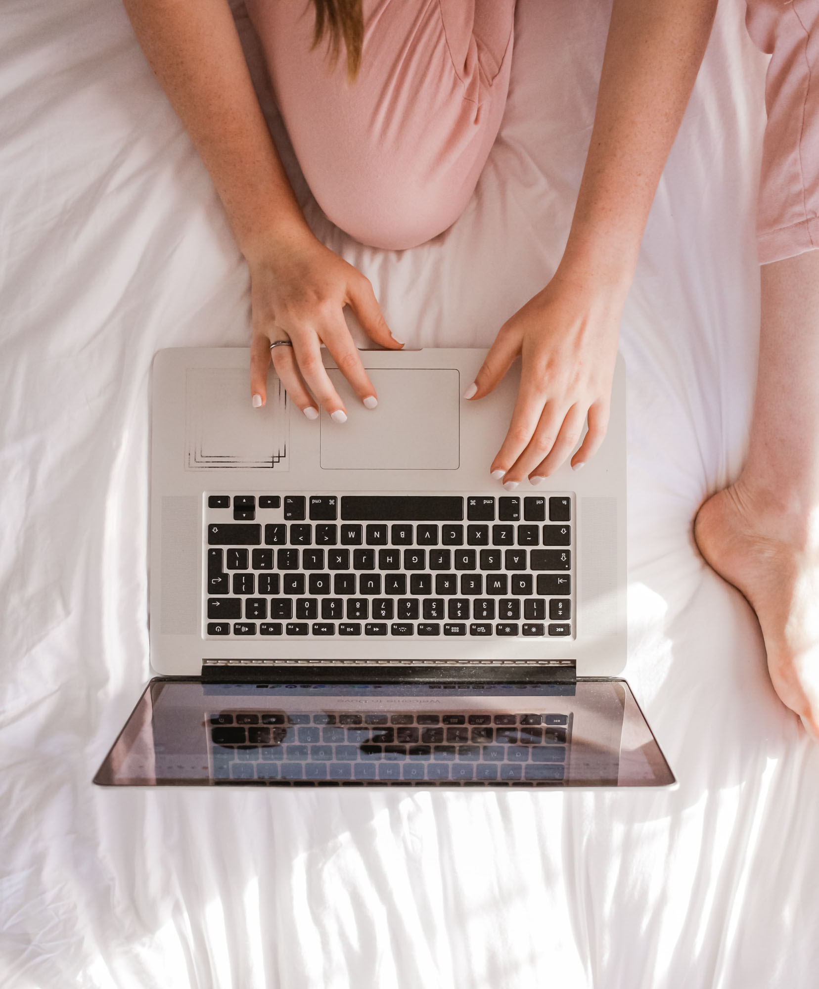 Girl sitting on a bed with a laptop writing SEO-friendly website copy